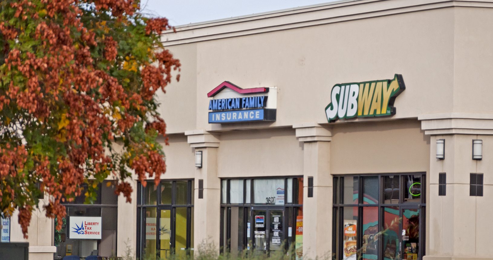 A subway restaurant with two signs on the side of it.