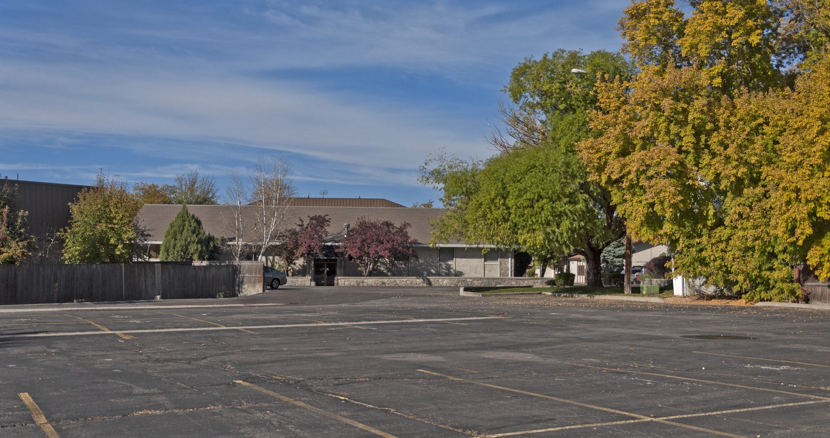 A parking lot with trees and buildings in the background.