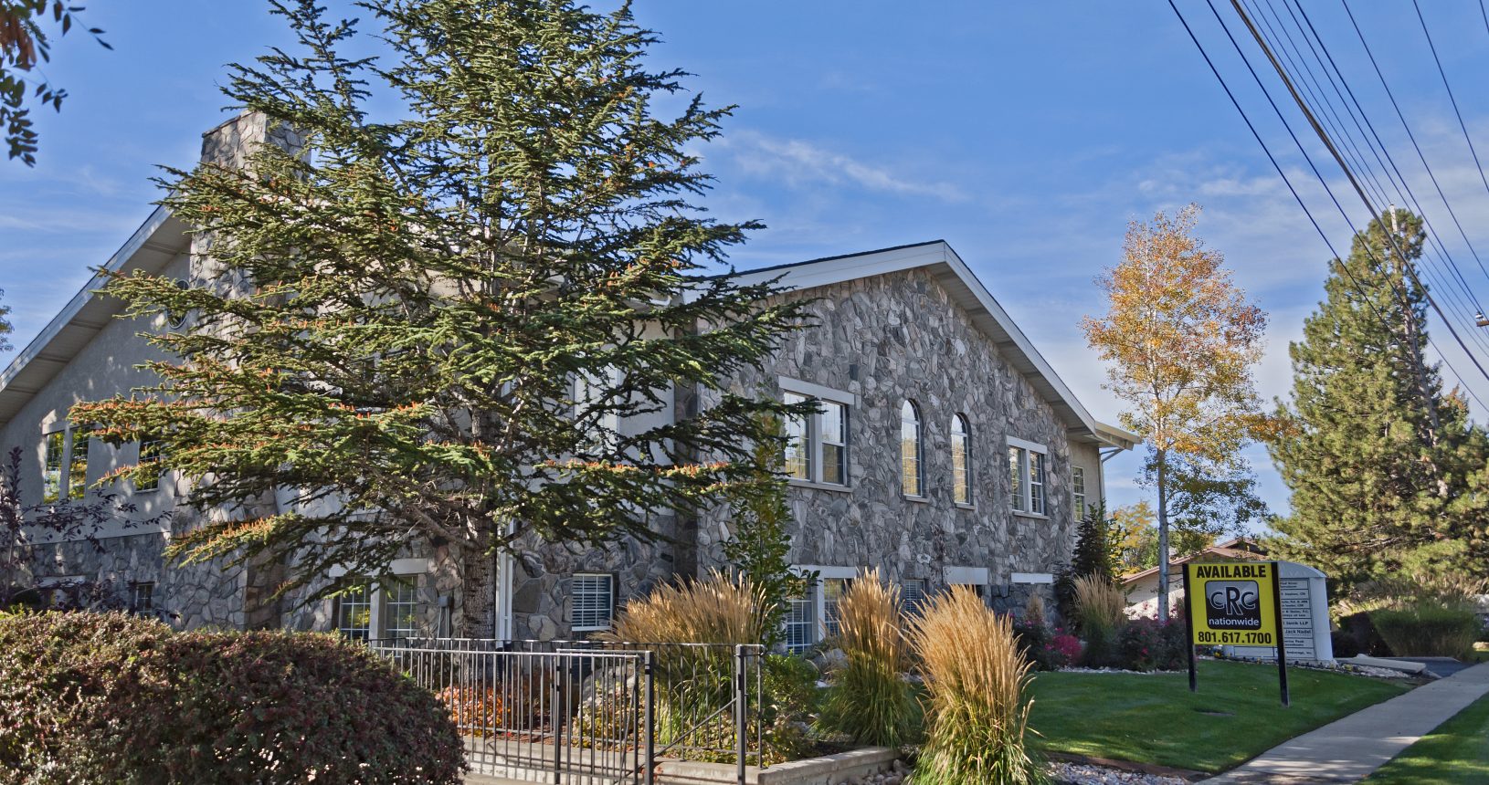 A stone building with trees and bushes in front of it.