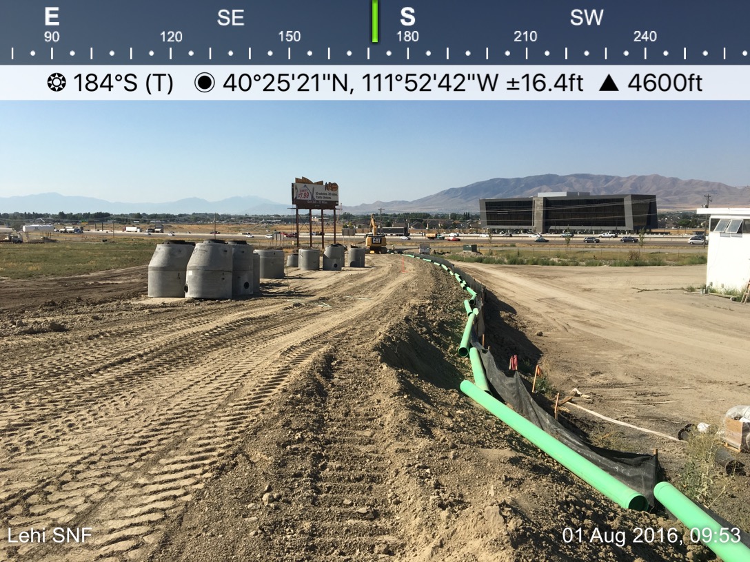 A man is standing in the dirt near some pipes.