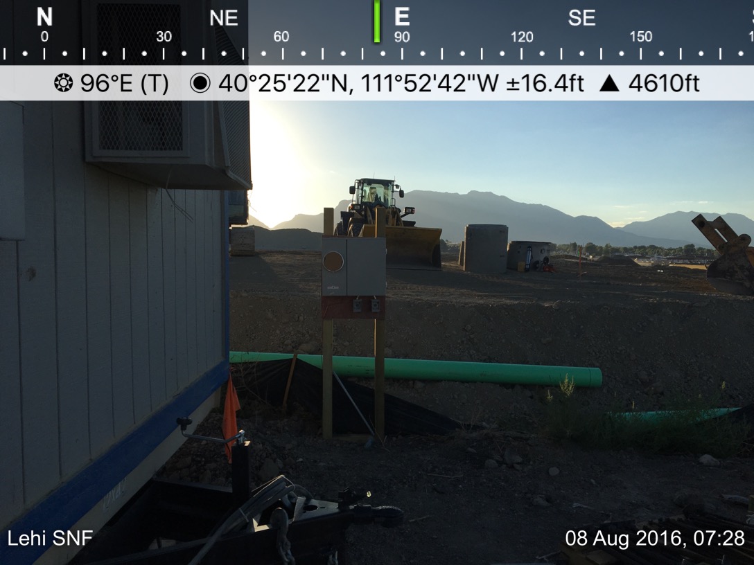 A tractor is parked in the distance near some mountains.