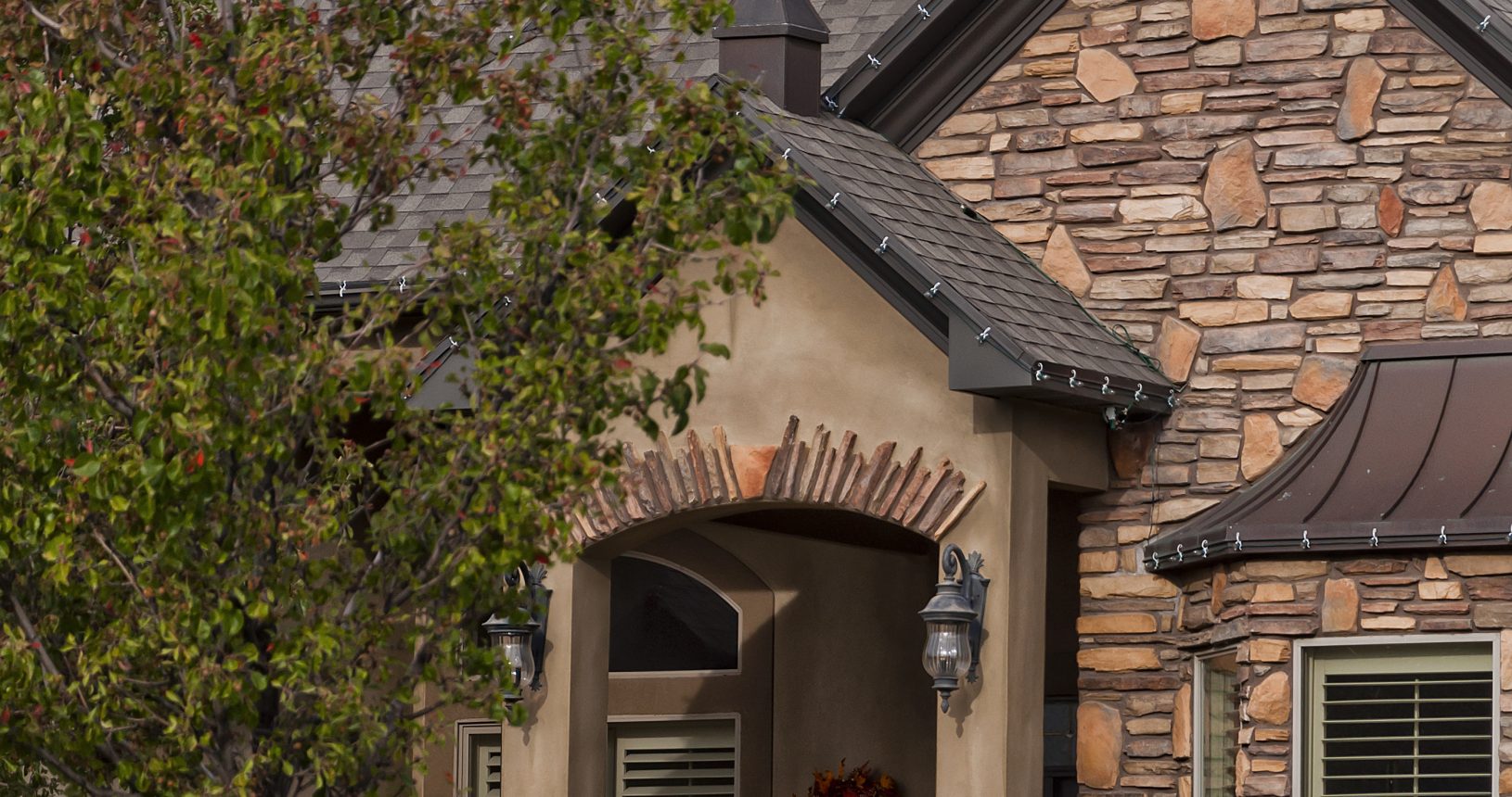 A brick and stone house with a brown roof.