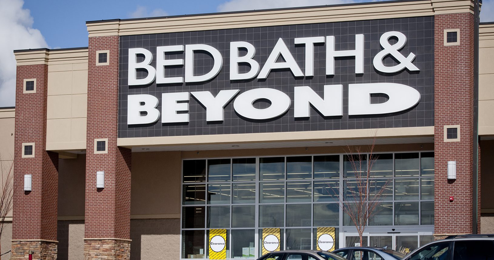 A bed bath and beyond store with cars parked in front of it.