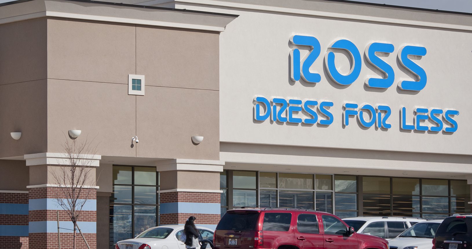 A woman is walking in front of a store.