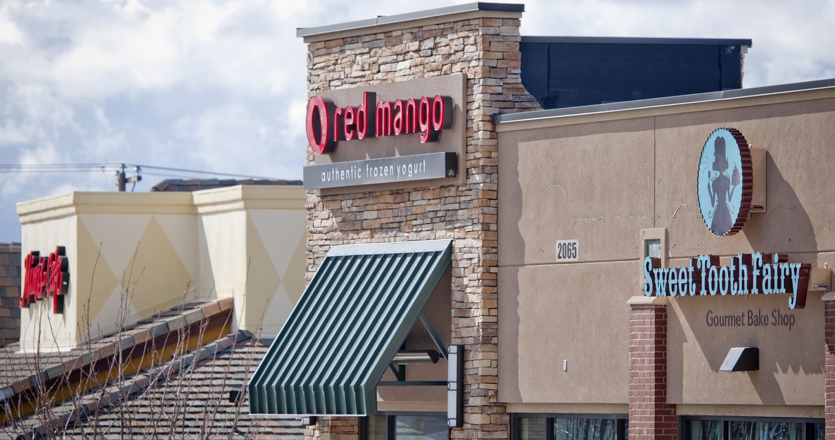 A restaurant with brick and stone exterior, awning and signs.