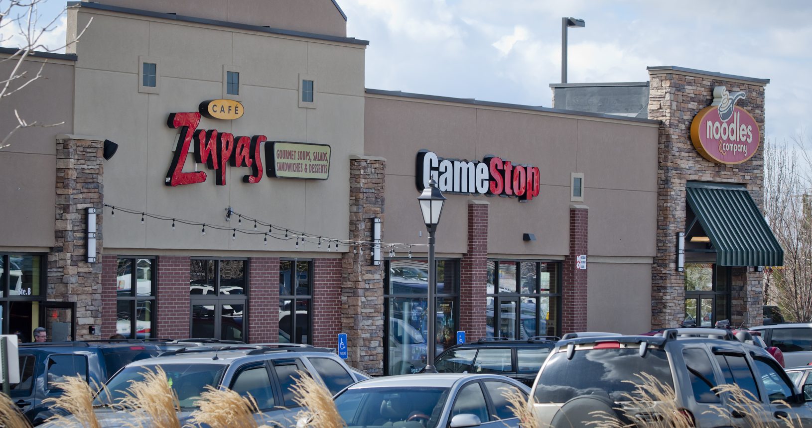 A street scene of a shopping center with cars parked in front.