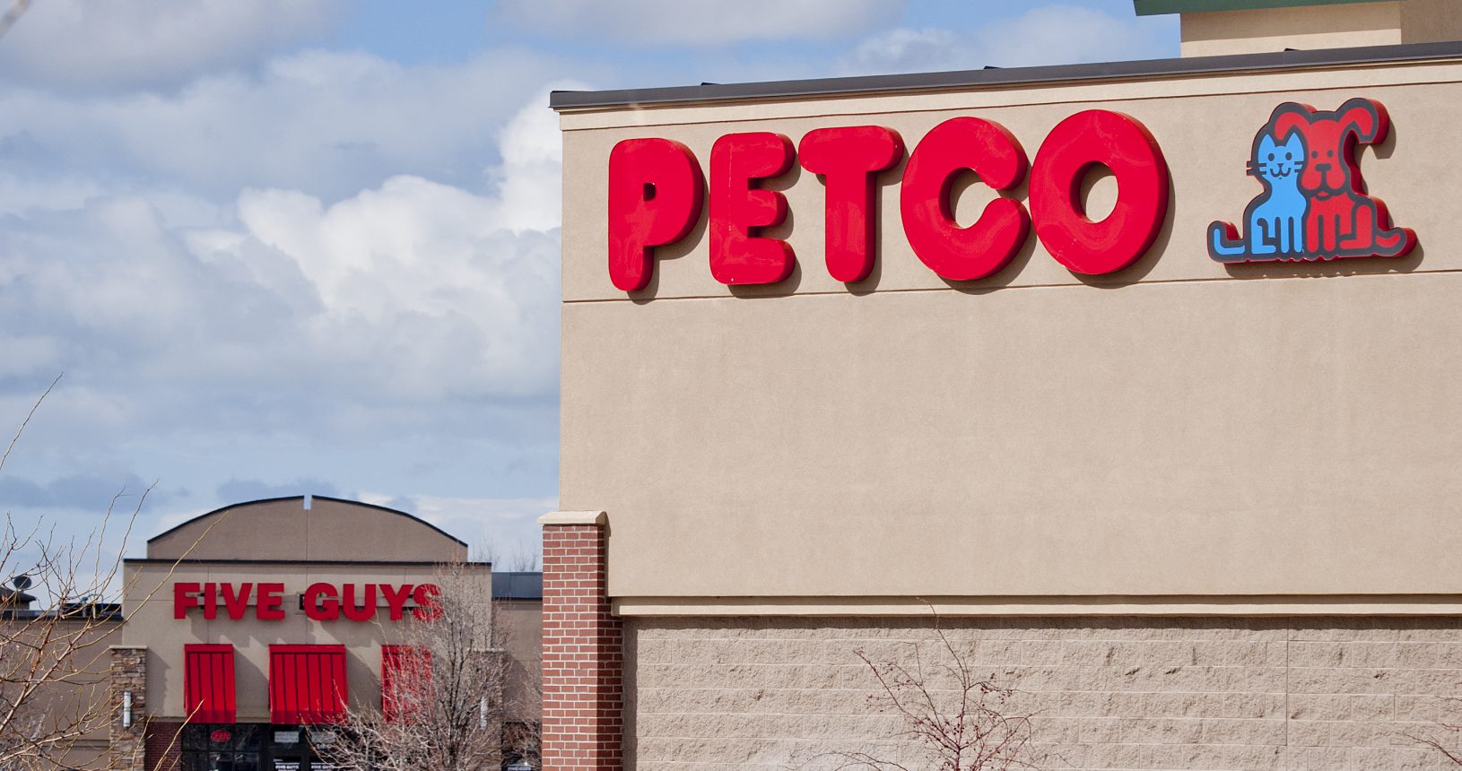 A petco store with cars parked in front of it.