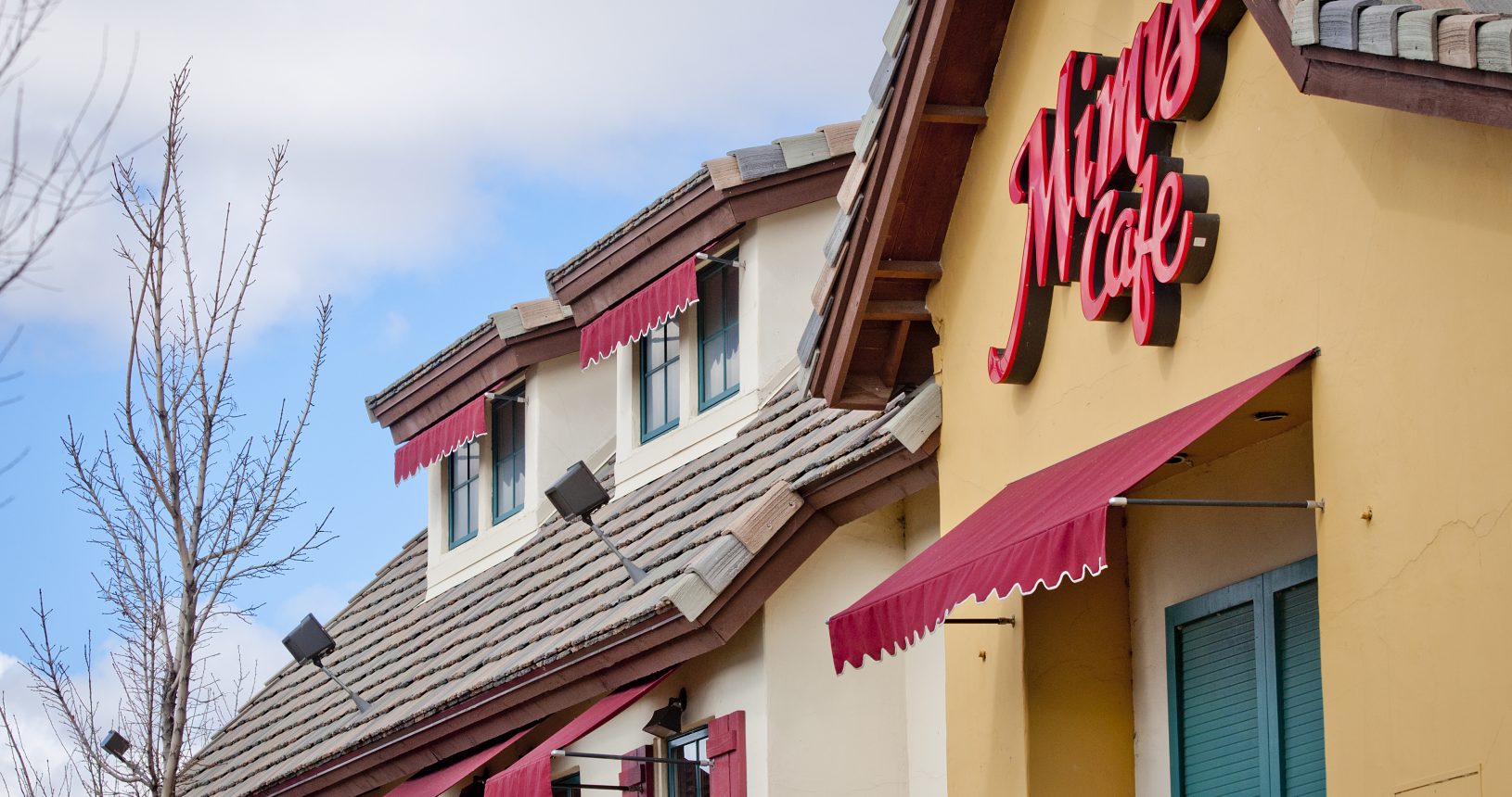 A large restaurant with red awnings on the side of it.