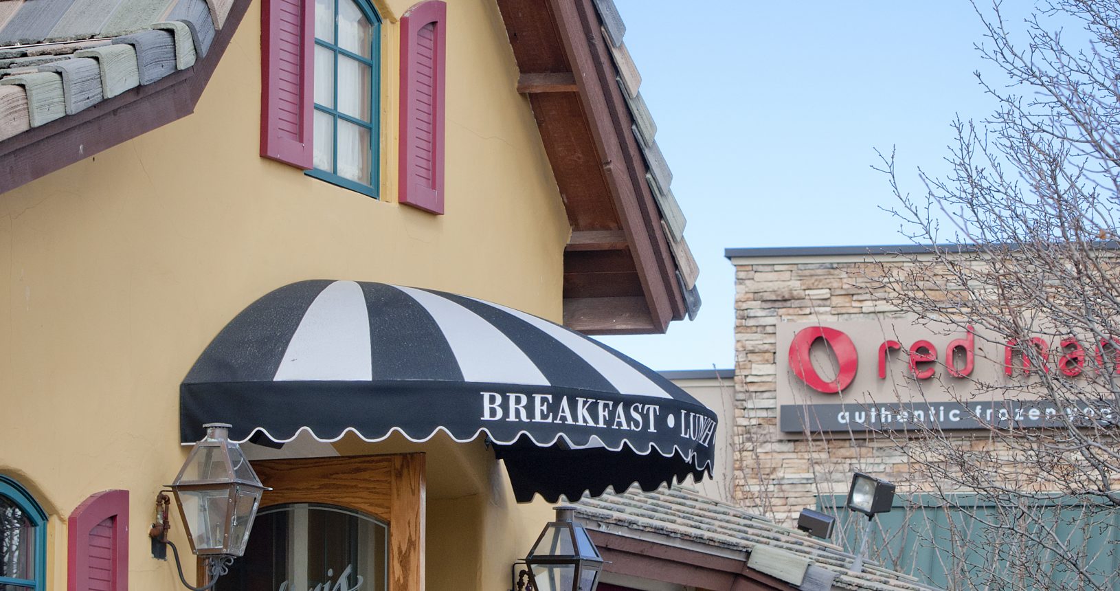 A restaurant with two people standing outside of it.