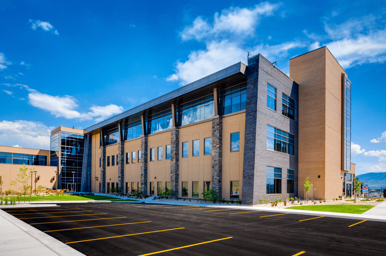 A large building with many windows and a parking lot.