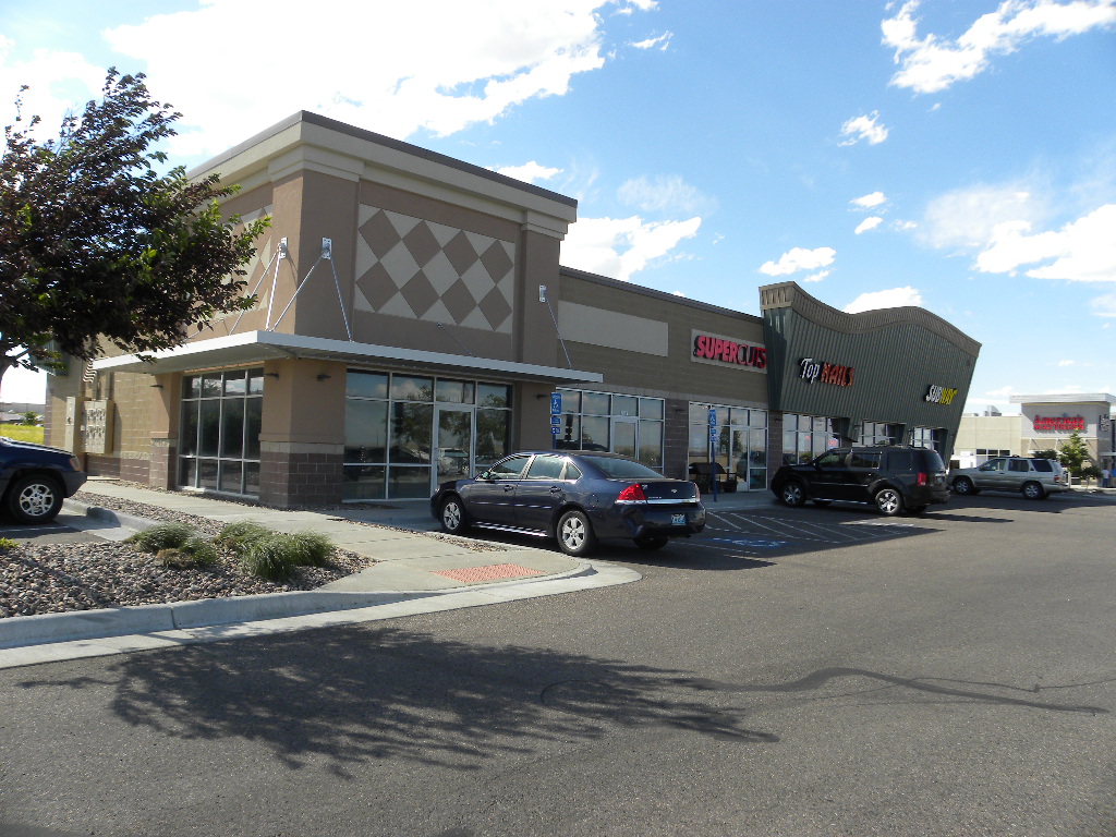 A large shopping center with cars parked in front of it.