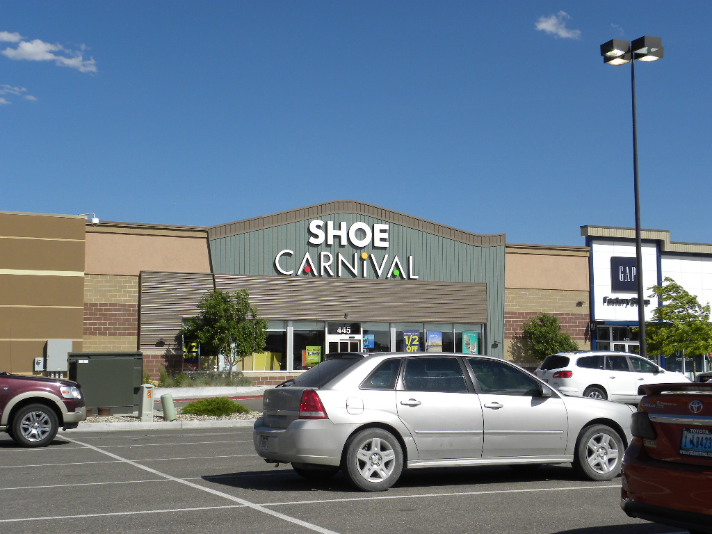 A car parked in front of a shoe carnival store.