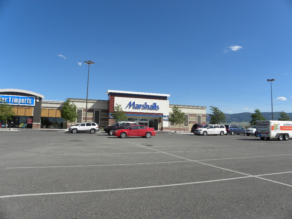 A large parking lot with cars parked in front of it.