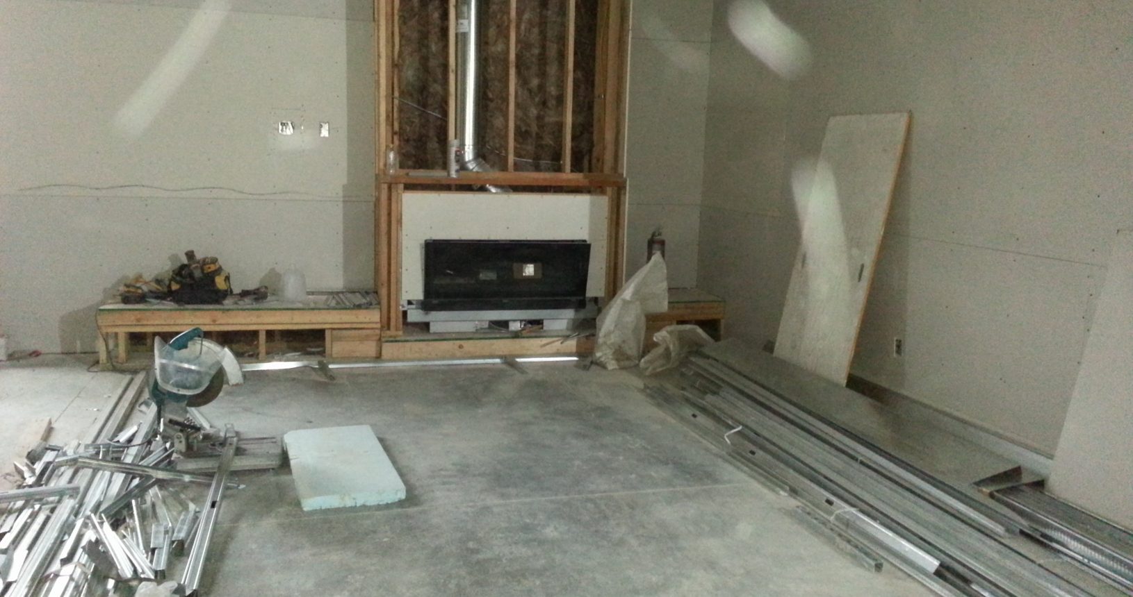 A room being remodeled with a fireplace and concrete floor.