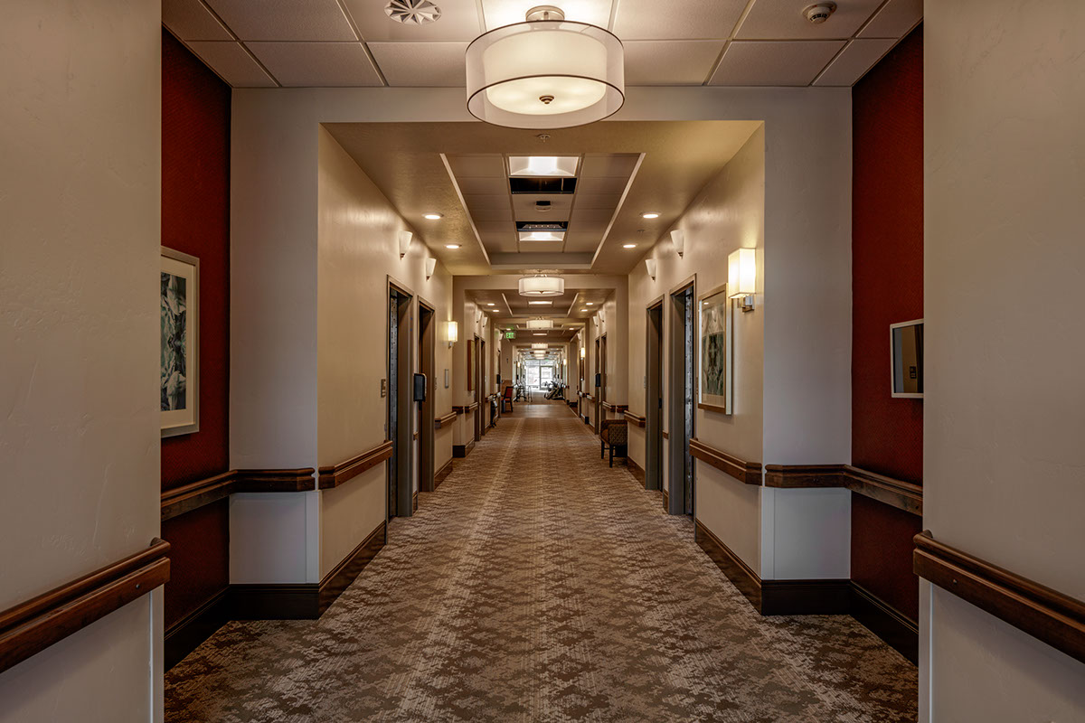 A hallway with many doors and lights on the ceiling.