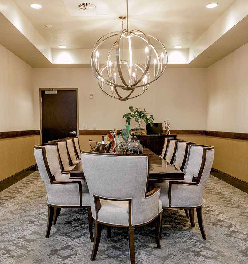 A dining room table with chairs and a chandelier.