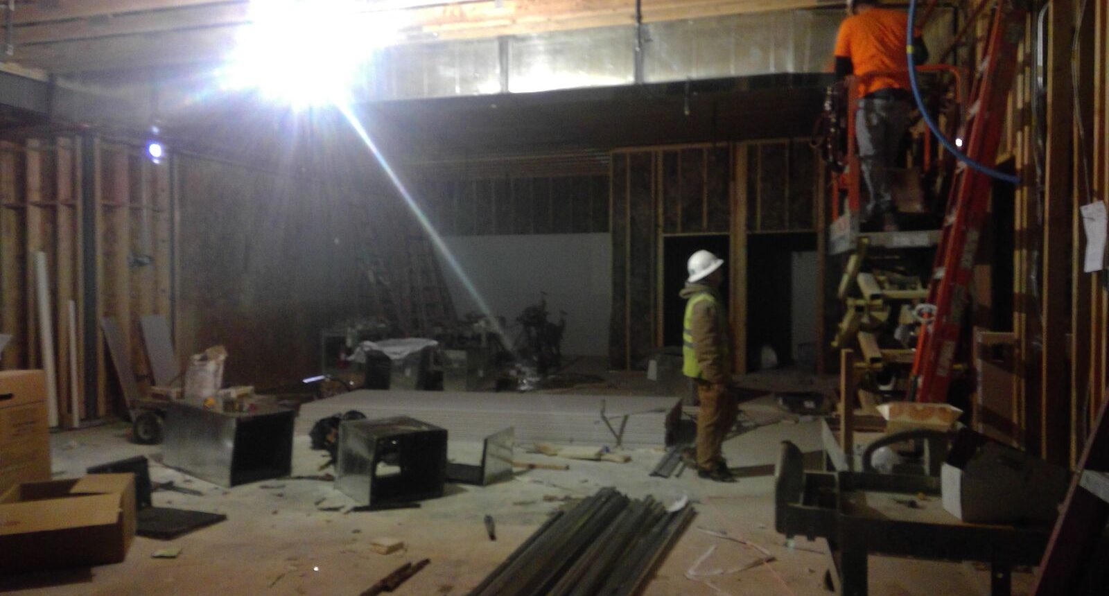 A man in yellow jacket standing next to construction equipment.