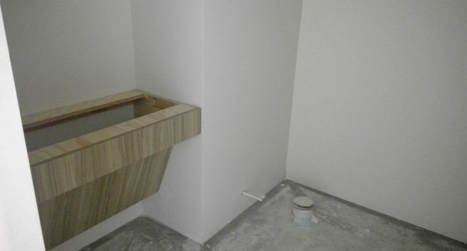 A bathroom with white walls and a wooden sink.