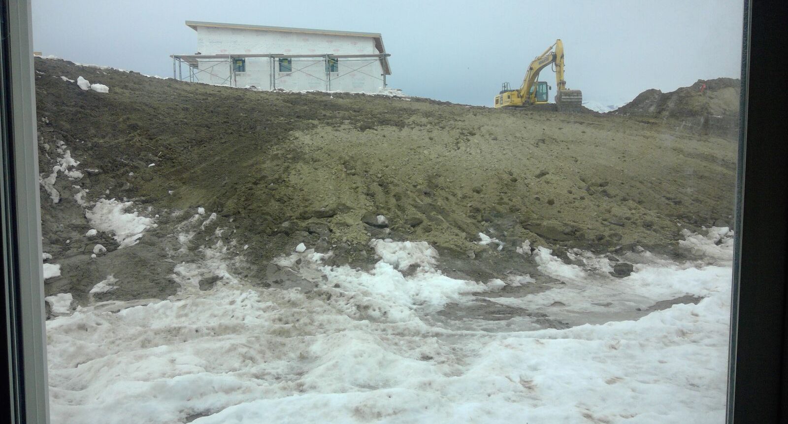 A house on the beach with a bulldozer in front of it.