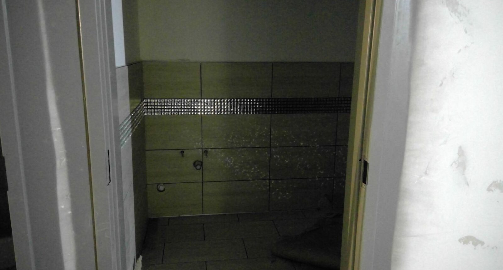 A bathroom with green tile and black border