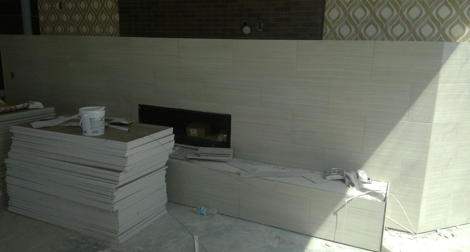 A fireplace in the corner of a room with white tile.