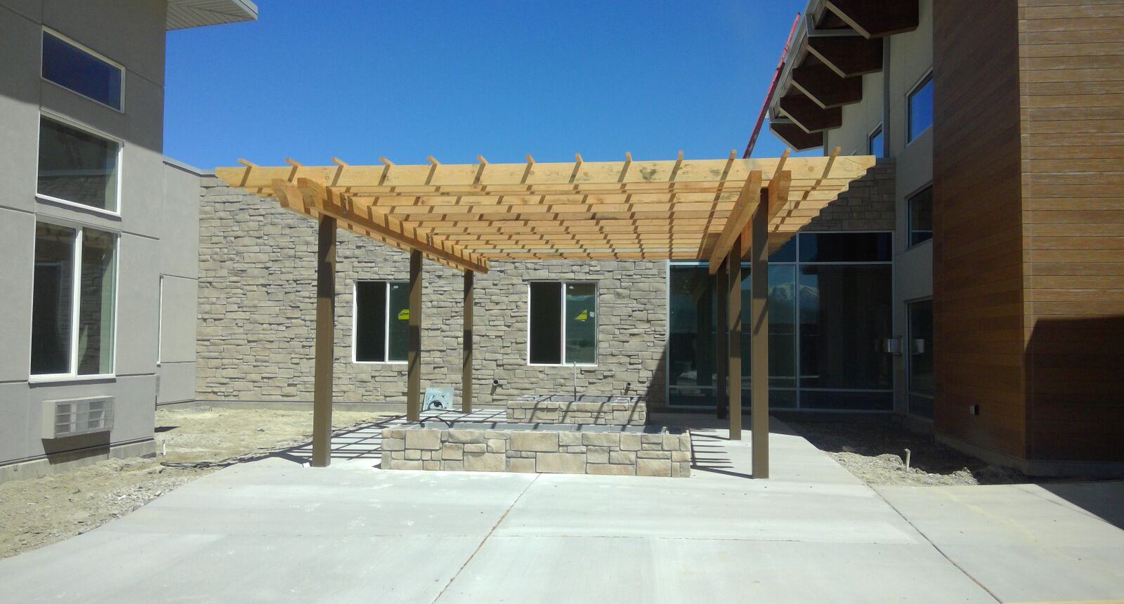 A building with a stone wall and a wooden pergola.