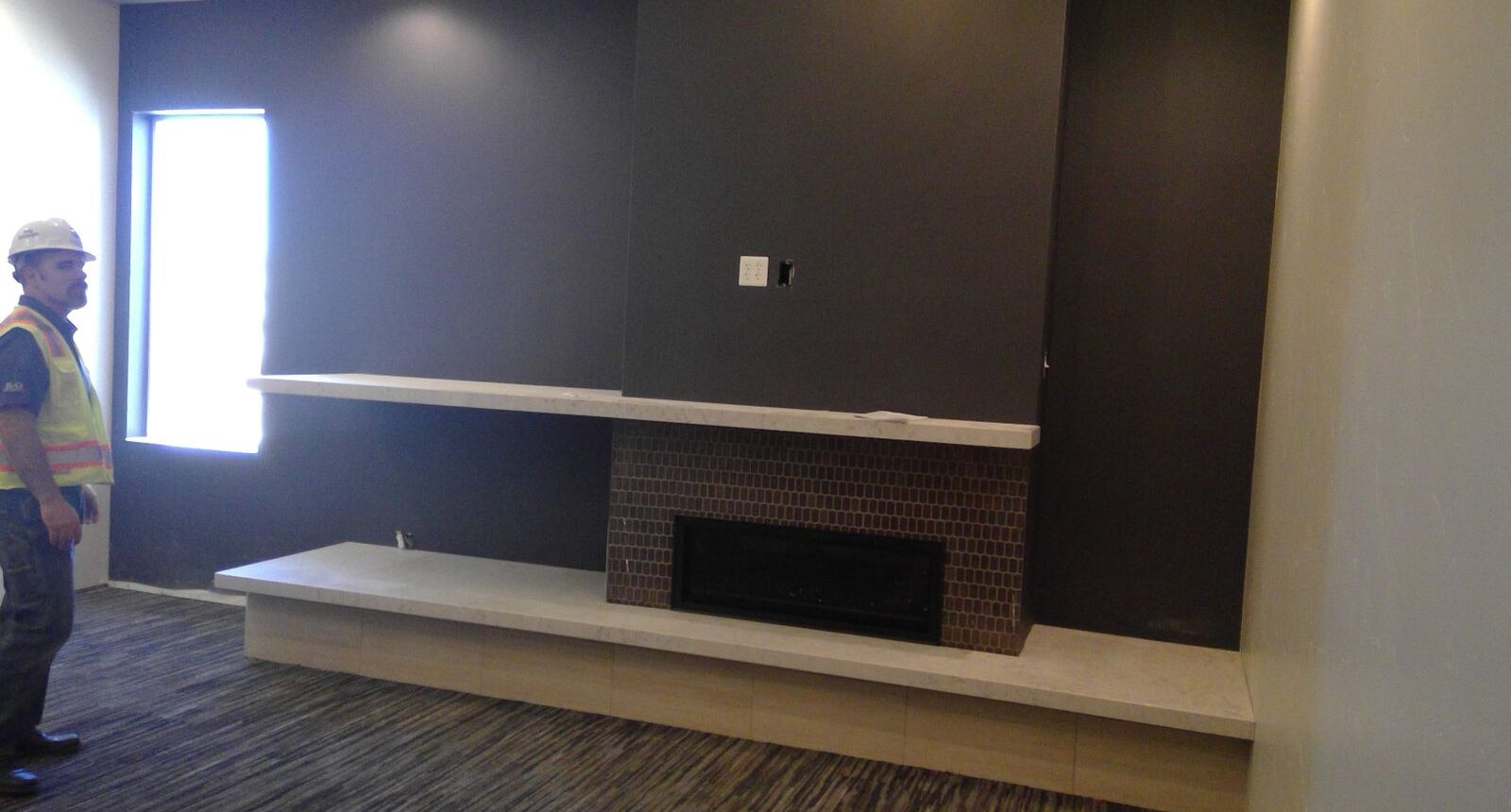 A fireplace in the corner of a room with dark walls.